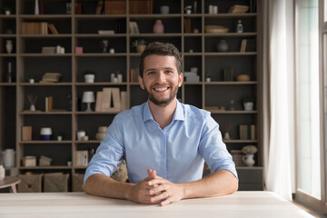 Smiling confident gen z male vlogger influencer business trainer job seeker speak online from home office or studio desk look at camera present idea lead webinar coaching session pass webcam interview