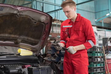 Mechanic. Auto service shop. Mechanic repairing engine, car battery under hood at repair shop
