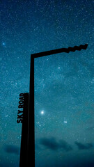 Wild Atlantic Way signpost silhouetted against star-filled sky on Sky Road during new moon.