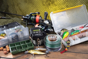 Sport fishing equipment on a table in a studio in a composition, against a wooden background and a fishing net.
