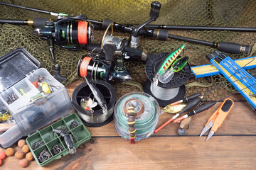 Sport fishing equipment on a table in a studio in a composition, against a wooden background and a fishing net.