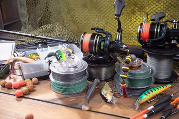 Sport fishing equipment on a table in a studio in a composition, against a wooden background and a fishing net.