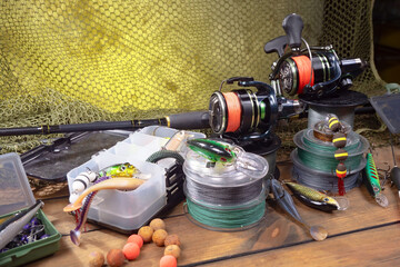 Sport fishing equipment on a table in a studio in a composition, against a wooden background and a fishing net.
