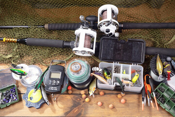 Sport fishing equipment on a table in a studio in a composition, against a wooden background and a fishing net.