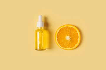 Serum bottle and orange slice on yellow background