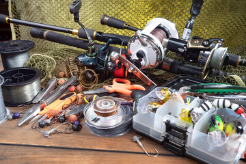 Sport fishing equipment on a table in a studio in a composition, against a wooden background and a fishing net.