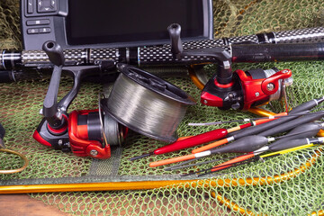 Sport fishing equipment on a table in a studio in a composition, against a wooden background and a fishing net.