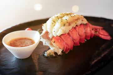 Grilled Lobster and vegetables on plate with a sauce cup