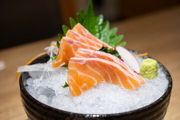 Salmon sashimi with vegetable and ice in a bowl, served in a restaurant