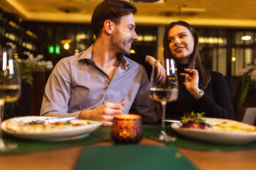Happy couple having romantic dinner date in a fancy restaurant. They eat delicious dishes.