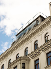 Old building exterior with a new built balcony at the rooftop. Luxury penthouse apartment with glass and modern materials. Real estate investment in a city in Europe.