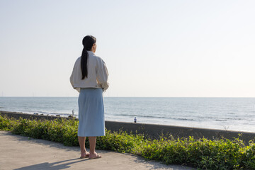 Woman standing alone looking at the ocean