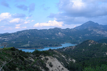 Majestic mountain landscape with serene lake nestled among rolling hills during a tranquil afternoon