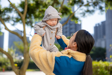 Obraz premium Happy mother holding baby under trees