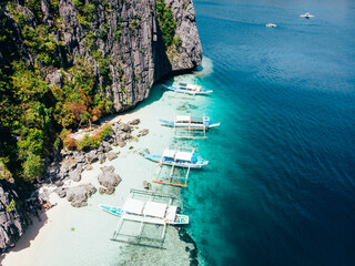Beautiful Aerial shot of a breathtaking lagoon, with blue, turquoise, crystal clear water filled with local boats in El Nido, Palawan, The Philippines. El Nido Stunning Beaches.