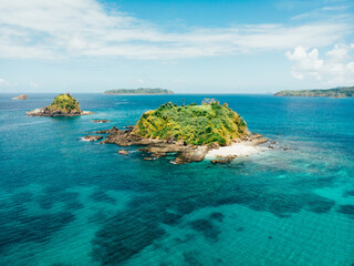 Aerial shot of Stunning Islands, with white sand beaches and blue and turquoise crystal clear water, filled with palm trees and coral reefs off shore. Dream Tropical Island Destination.