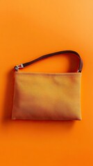Stylish golden-hued pouch bag with a woven strap, perfectly displayed on a vibrant orange background.