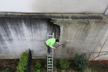 Homme qui nettoie un mur sale au jet haute pression