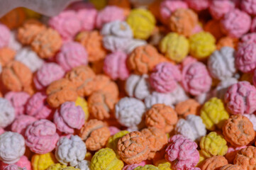 Colorful candy popcorn fills a festive container at a vibrant outdoor market during a sunny afternoon gathering in the city