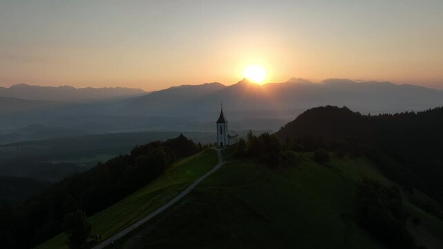 Aerial view of the Catholic church of Saint Primus and Felician at sunset in Jamnik, Kranj, Slovenia