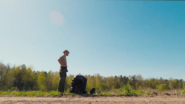 Tired hiker resting with backpack on forest road, spring sunny day