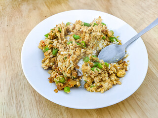 Homestyle nasi goreng kampung served on a white plate with green beans, egg, and seasoning, creating a rustic fried rice dish that highlights simple yet flavorful Indonesian comfort food tradition.