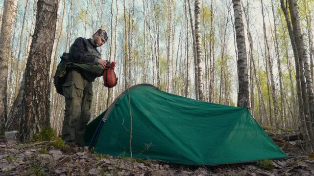 Camper Packing Sleeping Bag on a Sunny Morning in Forest