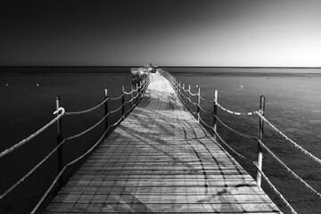Drewniany pomost prowadzący do morza, czarno-białe zdjęcie o nostalgicznej atmosferze  © Kacper