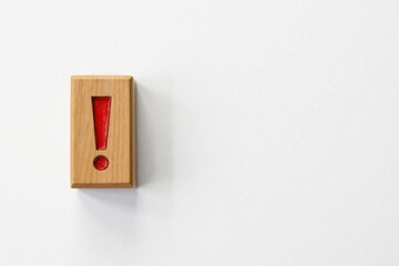 A single wooden block displaying a red exclamation mark on a plain white background, signifying important information or a crucial alert.