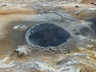 dark grey mud boiling and fuming in a geothermal mud pot in Namaskard geothermal area in Iceland