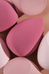 A set of makeup sponges on a pink background.