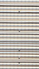 Wide shot of corrugated silver metal siding with visible bolts, facade, silver