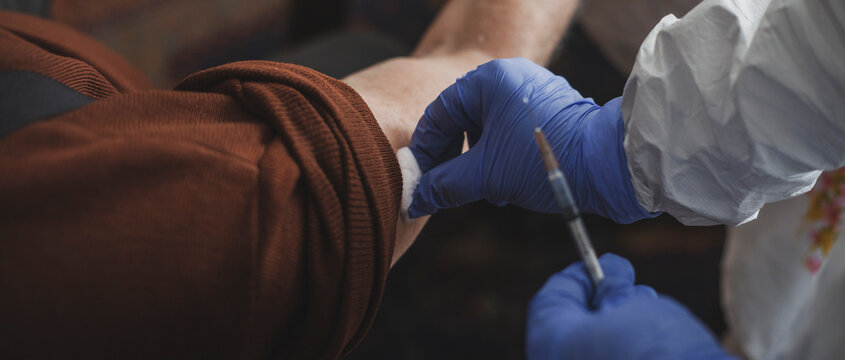 Doctor in protective suit vaccinating elderly man at home during epidemic - Powered by Adobe