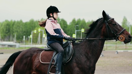 A Young Equestrian Enthusiast Riding a Beautiful Brown Horse in an Expansive Outdoor Arena