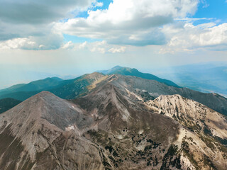 Aerial image of Pirin Mountains, Bulgaria, jagged peaks cutting through summer sky, rocky terrain...