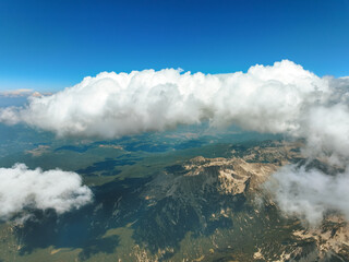 Drone capturing majestic Pirin Mountains, Bulgaria, steep rocky peaks stretching into distance, scattered clouds casting soft shadows, crisp summer atmosphere over alpine wilderness. Tourism