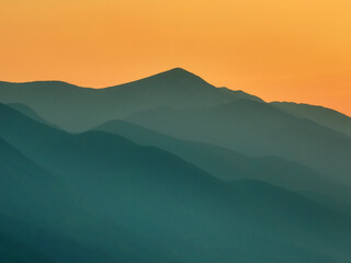 Obraz premium Drone view over Pirin Mountains, Bulgaria, during silhouette summer sunset, silhouettes of ridges blending into warm horizon, peaceful natural beauty of Balkan landscape. Travel, tourism