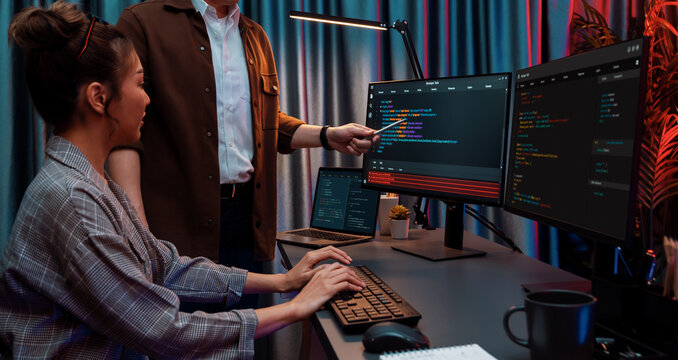 IT developers discussing with point to intelligent website development coder system running data online two screens information technology at neon light room at modern office. Infobahn.