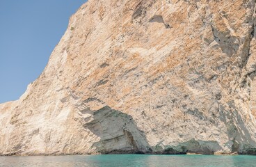 Turquoise waters gently lap against impressive cliffs, showcasing unique rock formations on a sunny...