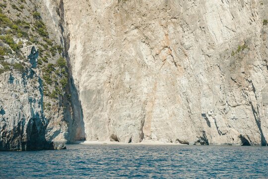 Bright sun reflects on calm waters as visitors take in the impressive cliffs of Greece during summer. The tranquil atmosphere invites relaxation and exploration of this beautiful landscape