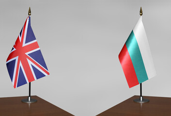 Tabletop flags of United Kingdom and Bulgaria on stands on a gray blurred background
