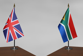 Tabletop flags of United Kingdom and South Africa on stands on a gray blurred background