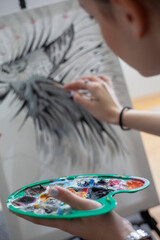 Woman Painting on Canvas with Brushes and colors