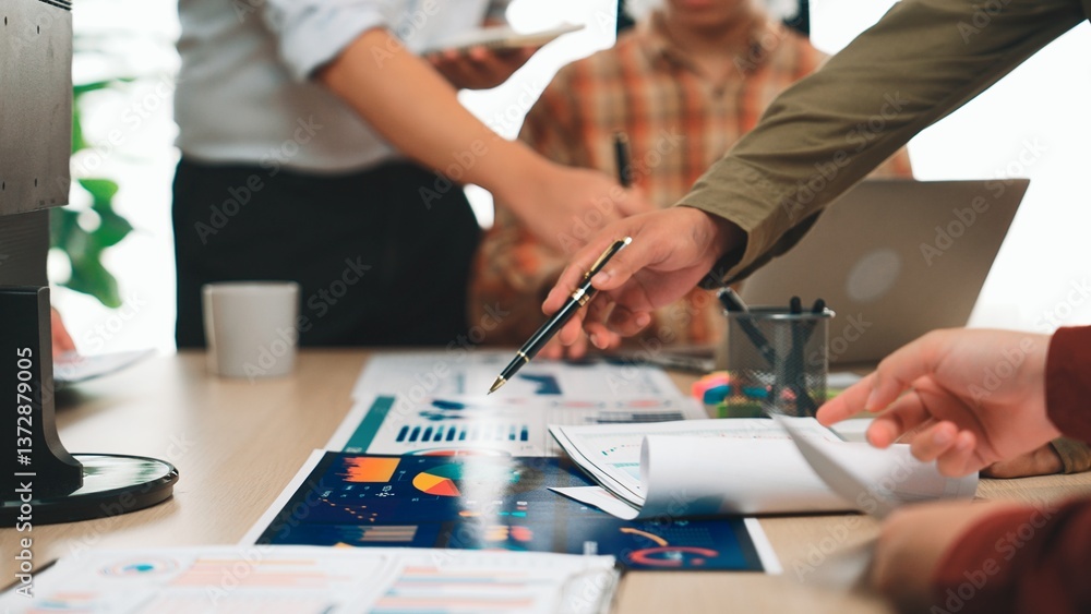 Poster a business team collaborates in an office environment, analyzing charts and documents on a table. fo