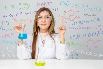 Beautiful Asian scientific researcher holding a liquid solution with science or chemistry formula..