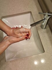 Hands lathering soap before rinsing at a modern bathroom sink during an evening routine