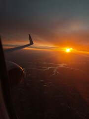 Sunset over sprawling landscapes as airplane wing embraces twilight sky during tranquil evening...