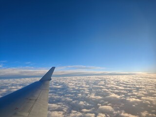 Fototapeta premium Airplane wing above fluffy clouds against clear blue sky 