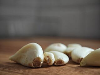 Fresh garlic cloves resting on a wooden cutting board illuminated by soft kitchen light in a serene...