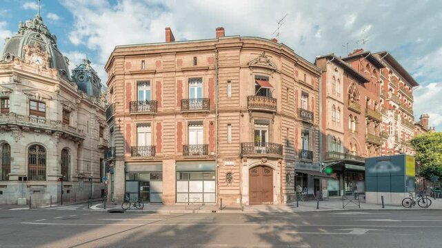 Panorama showing historic brick facades at Rue du Languedoc and Theodore Ozenne intersection timelapse in Toulouse, France. Shops, cafes, road traffic near Carmes metro station in vibrant city center